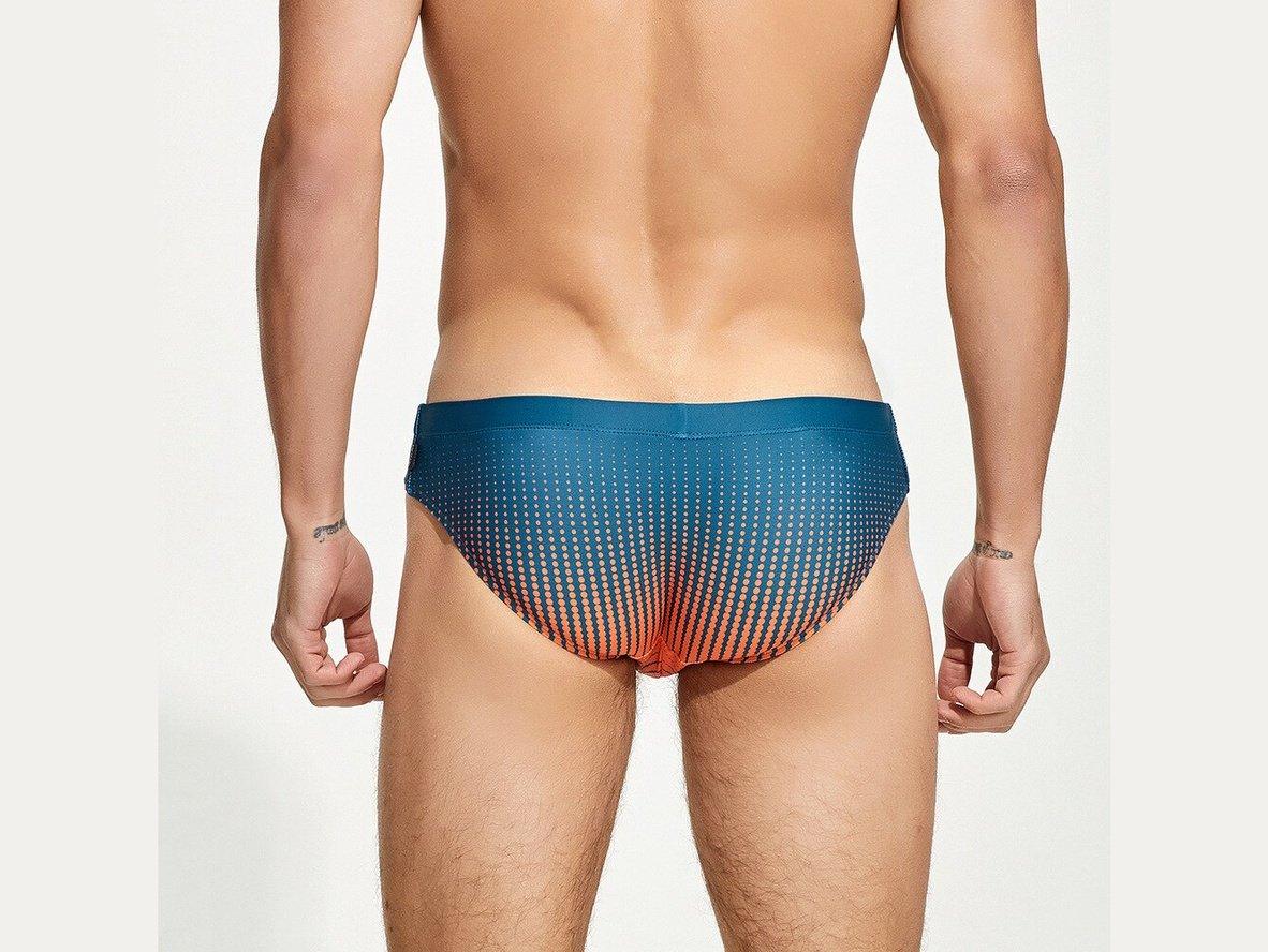 Back view of teal to orange gradient dot swim briefs on male model