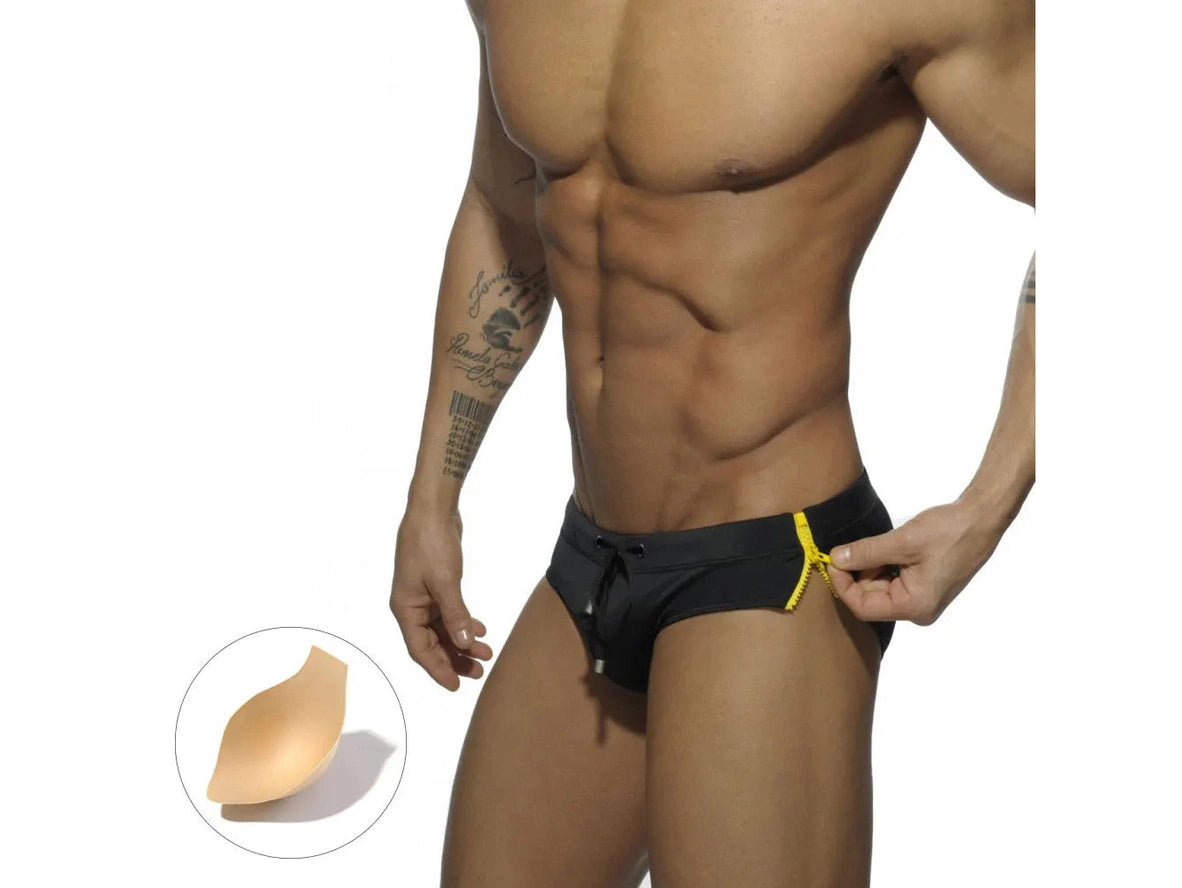 Black swim briefs with yellow zipper and beige pushup pad inset