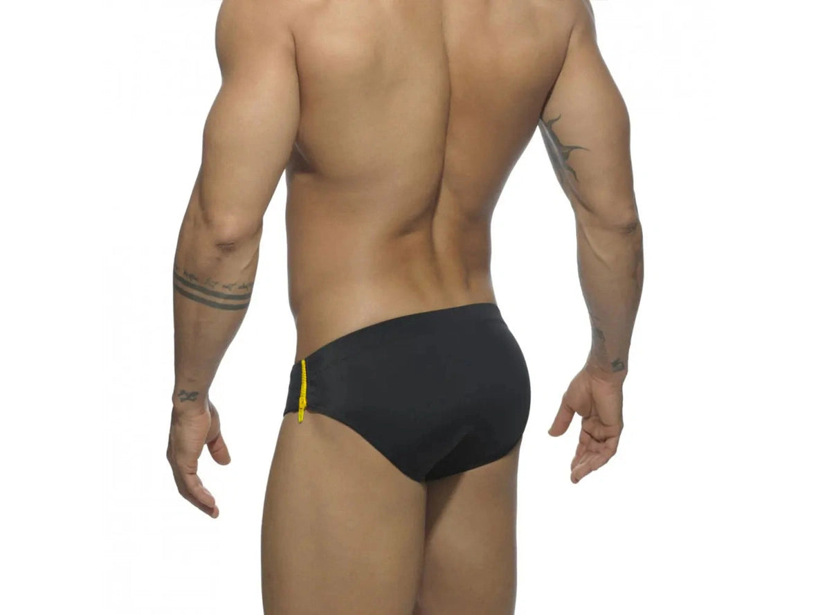 Rear view of black swim briefs with yellow side zipper on model