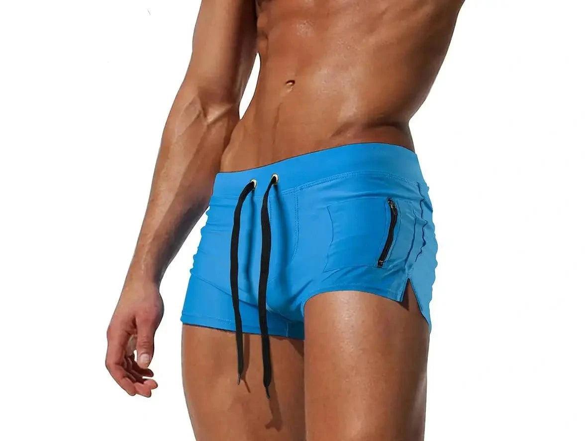 Bright blue low-rise men's swim trunks with side zipper pocket and drawstring