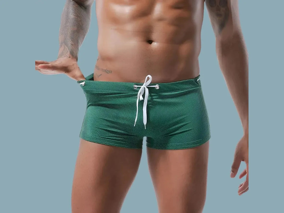 Emerald green low-rise men's swim trunks with subtle micro-dot texture