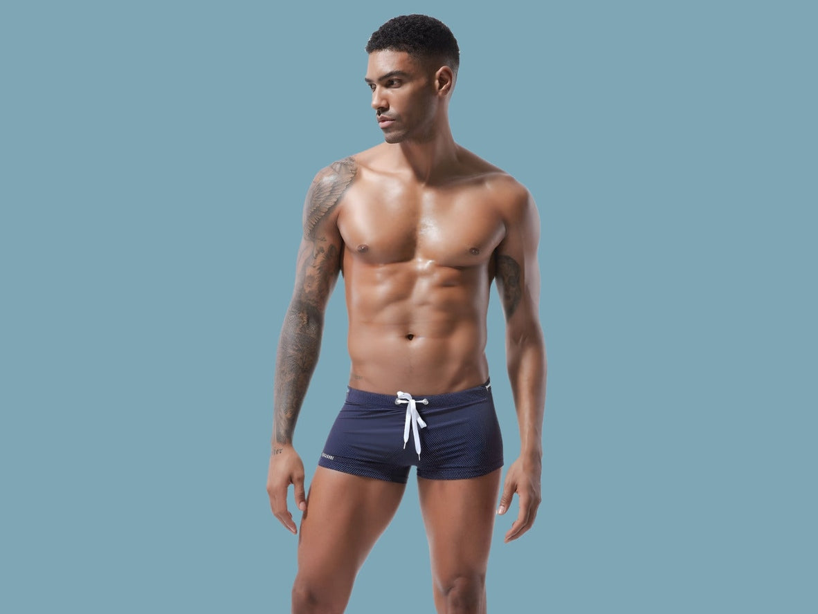 Navy blue low-rise men's swim trunks with fine dotted texture and reflective sheen