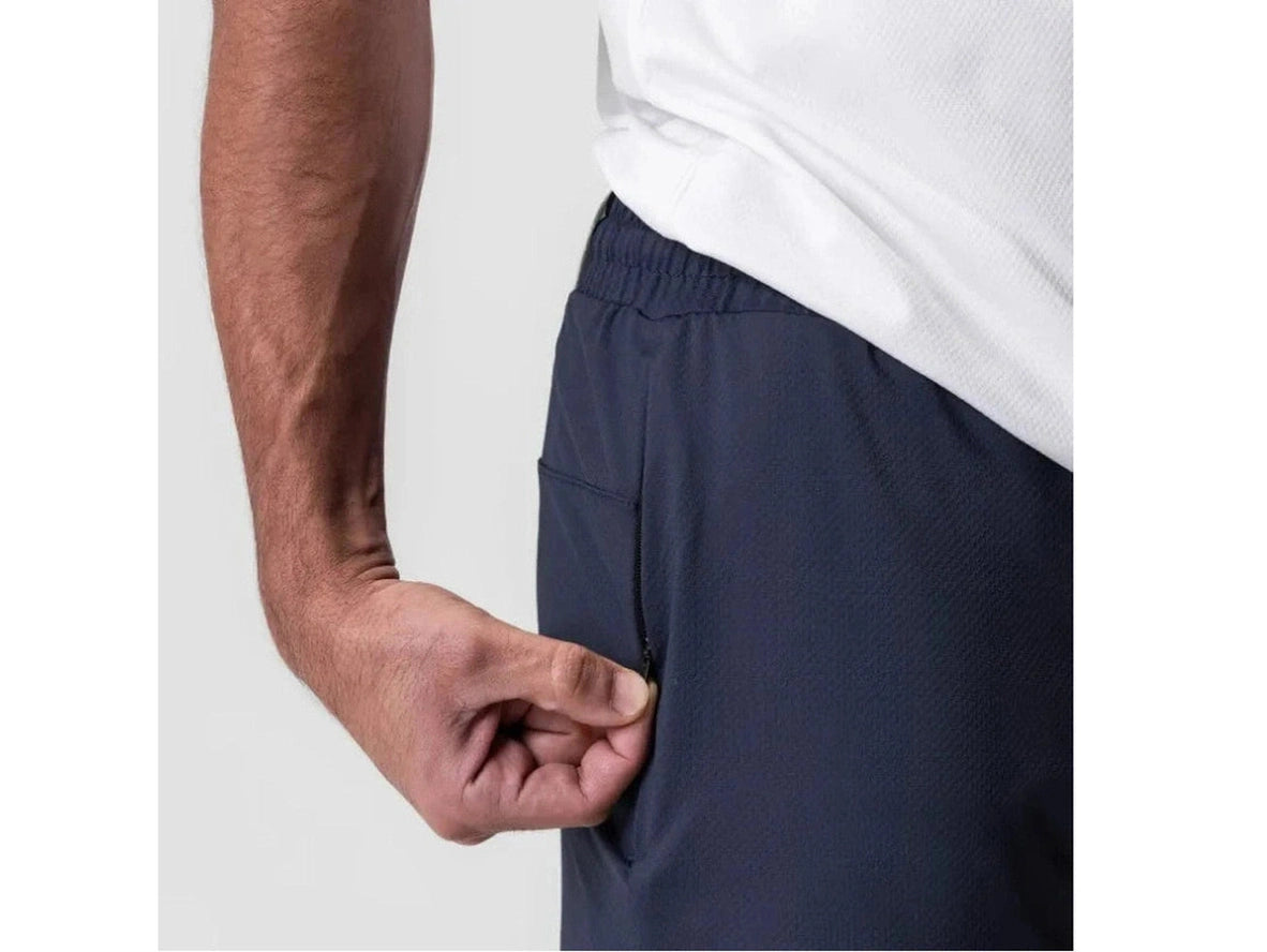 Close-up of navy blue shorts with hand opening zippered thigh pocket