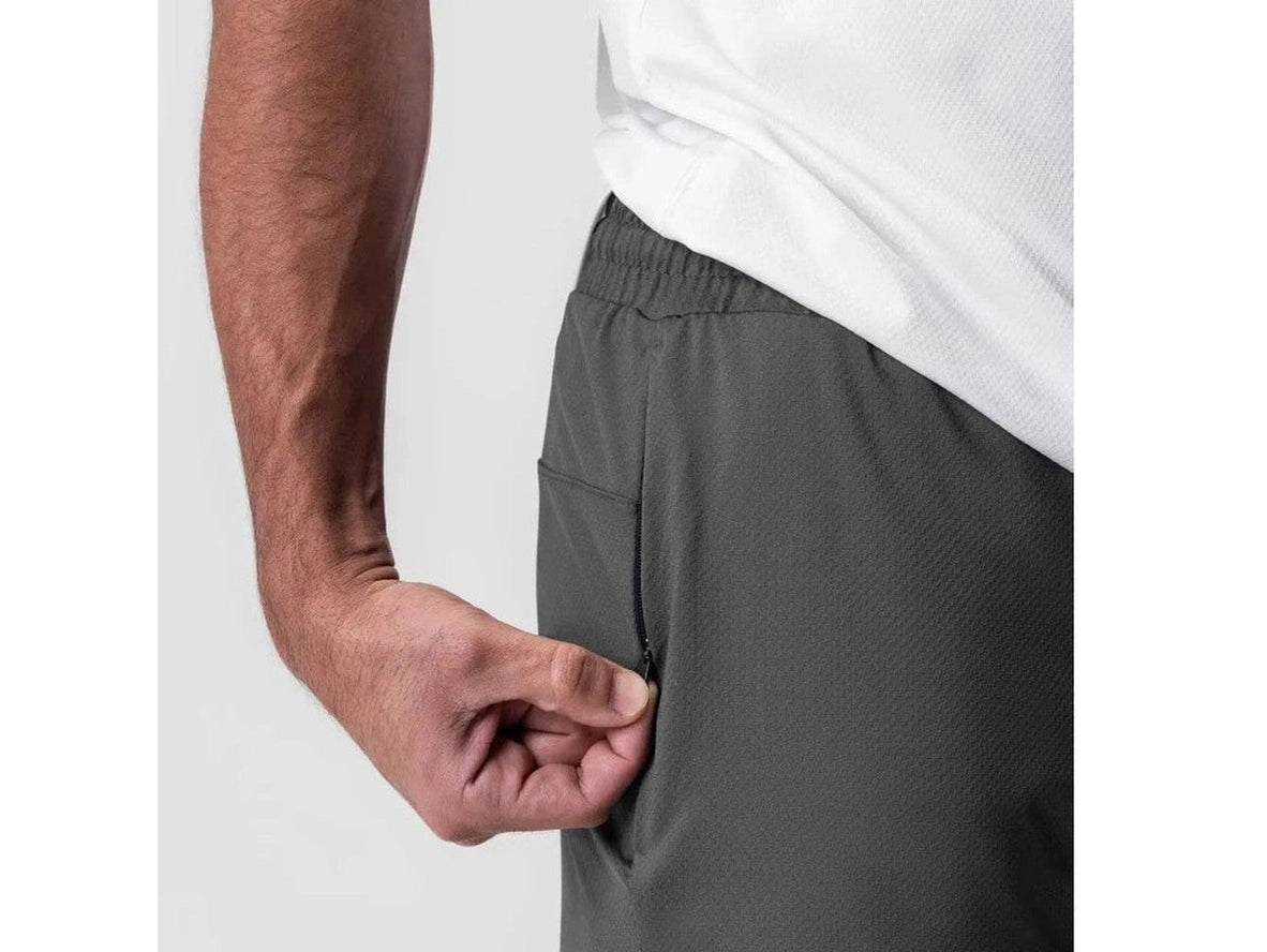 Dark gray gym shorts side profile with hand accessing zippered pocket