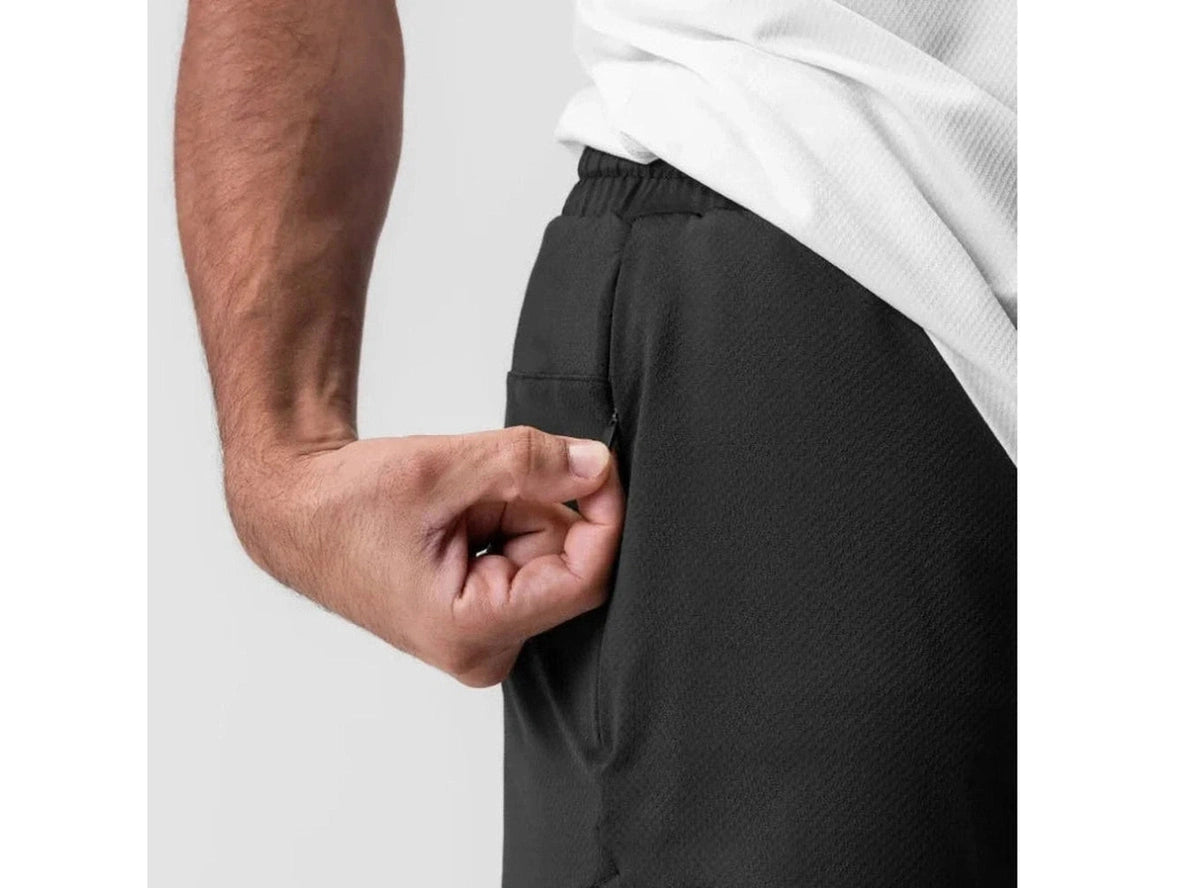 Black athletic shorts close-up showing hand in zippered side pocket