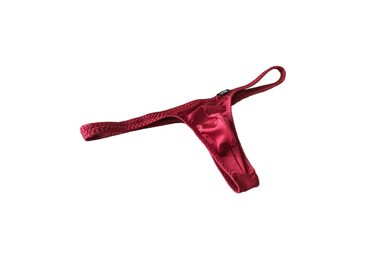 Red satin thong on a beige fabric background with 'UNDER MOON' branding.