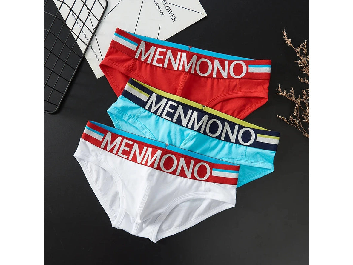 Three pairs of women's briefs by MENMONO are arranged diagonally on a dark surface. The briefs are in red, light blue, and white, each featuring a wide elastic waistband with the brand name 'MENMONO' printed in white, accented with blue, yellow, and navy stripes.