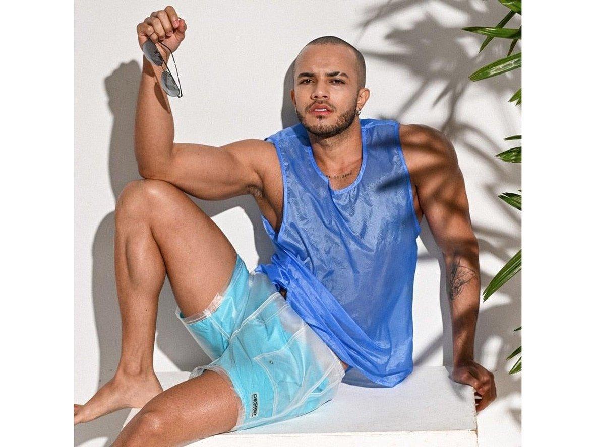 Blue transparent swim shorts worn by model with sleeveless mesh top