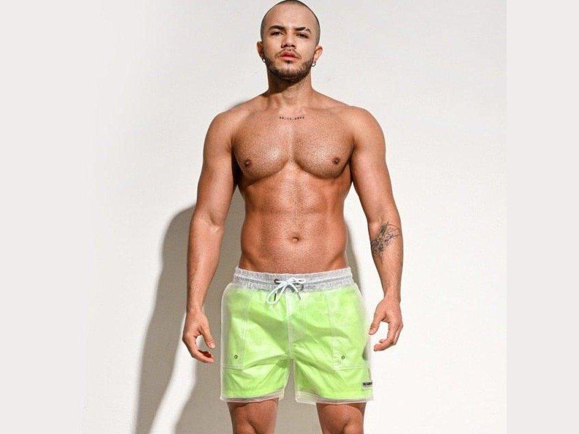 Bright neon green sheer swim shorts for men with visible stitching and pockets