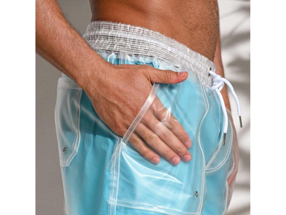 Close-up of light blue sheer swim shorts with hand in pocket and seam details